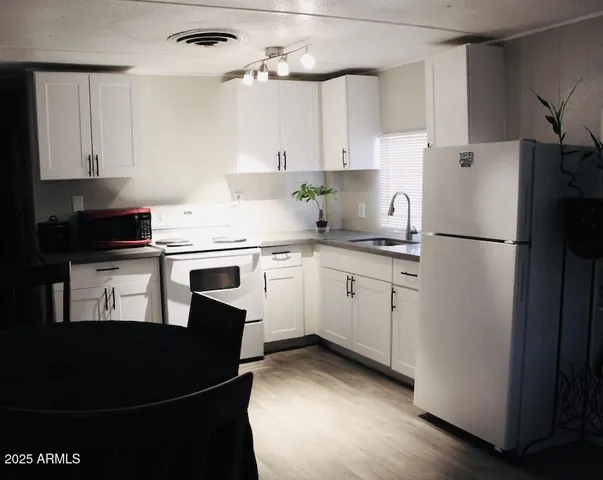 a kitchen with a white refrigerator a sink and cabinets