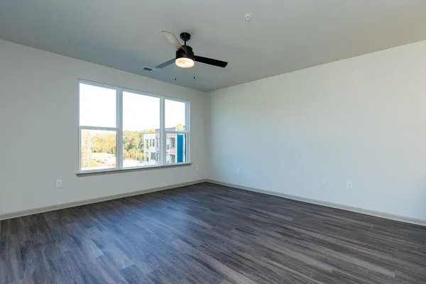 a view of an empty room with wooden floor and a window