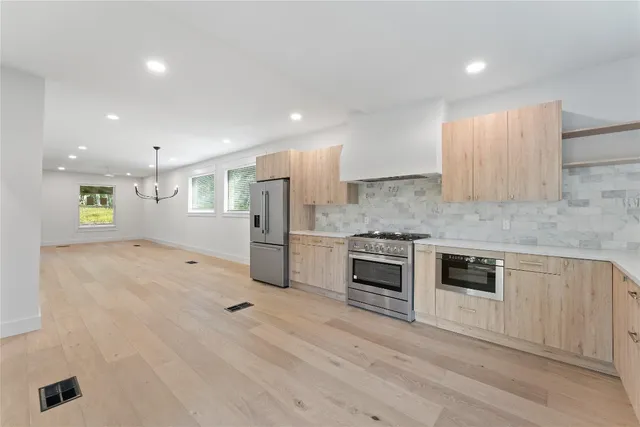 a kitchen with stainless steel appliances granite countertop a stove a sink and a refrigerator