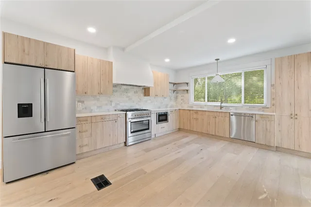 a kitchen with granite countertop a refrigerator a sink and white cabinets