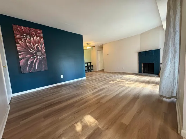 a view of an empty room with window and wooden floor