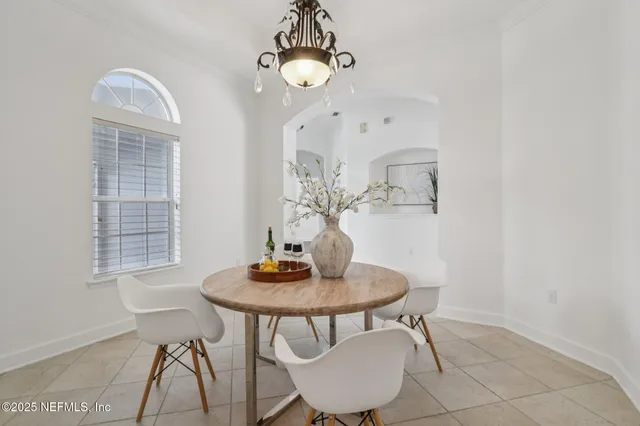 an empty room with wooden floor chandelier and windows