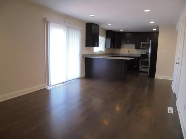 a view of kitchen with kitchen island microwave and wooden floor