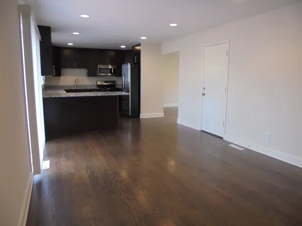 a view of kitchen with kitchen island stainless steel appliances counter space and wooden floor