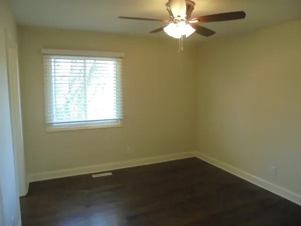 an empty room with a window and a fan