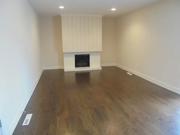 an empty room with wooden floor and fireplace