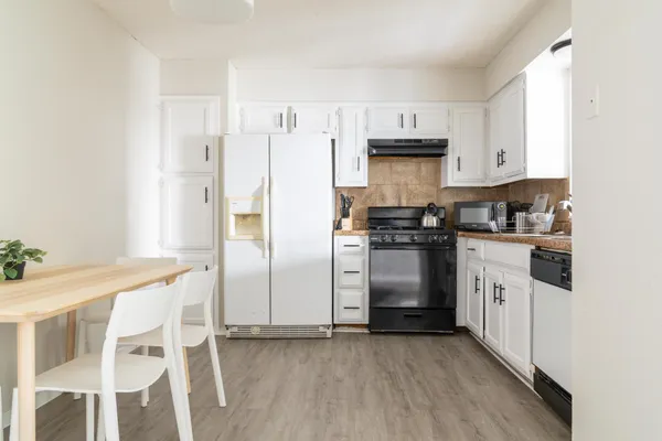 a kitchen with granite countertop a refrigerator stove and white cabinets