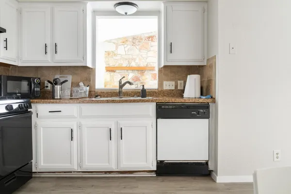 a kitchen with granite countertop a sink cabinets and a window