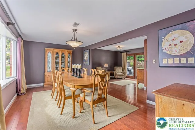 a dining room with wooden floor a chandelier a wooden table and chairs