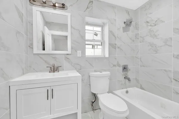 a bathroom with a toilet sink vanity tub and mirror