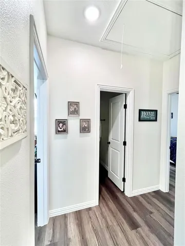 a view of a hallway with wooden floor and cabinets