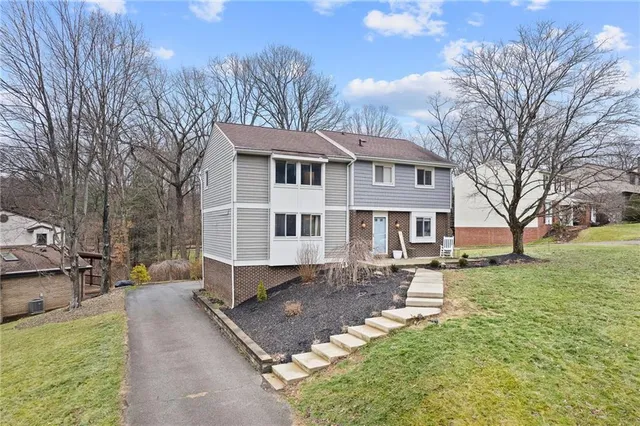 a front view of a house with a yard covered with trees