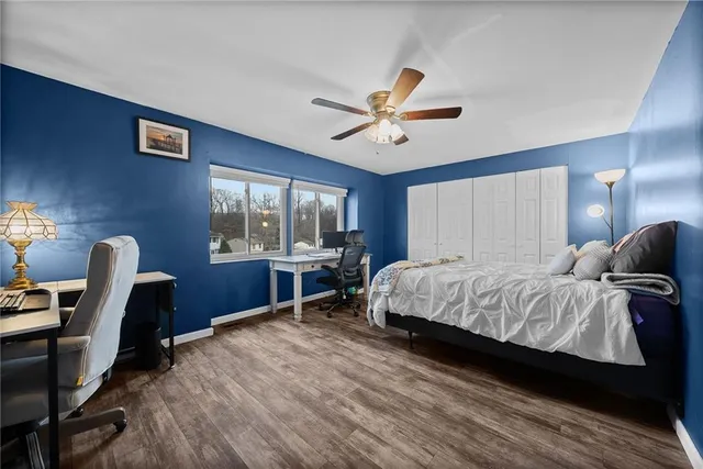 a bedroom with a bed a desk and chair with wooden floor