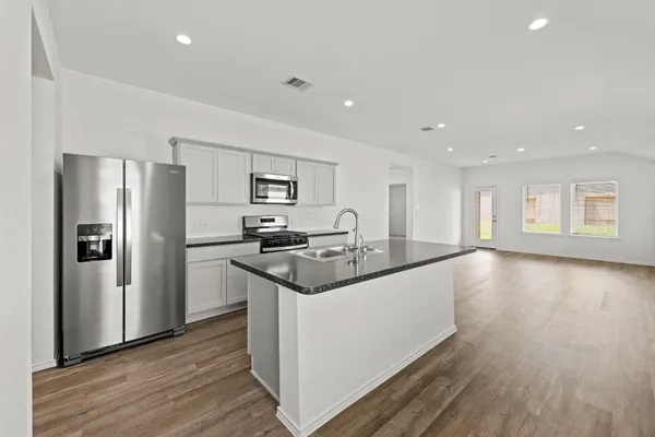 a kitchen with stainless steel appliances granite countertop a refrigerator a stove and a wooden floors