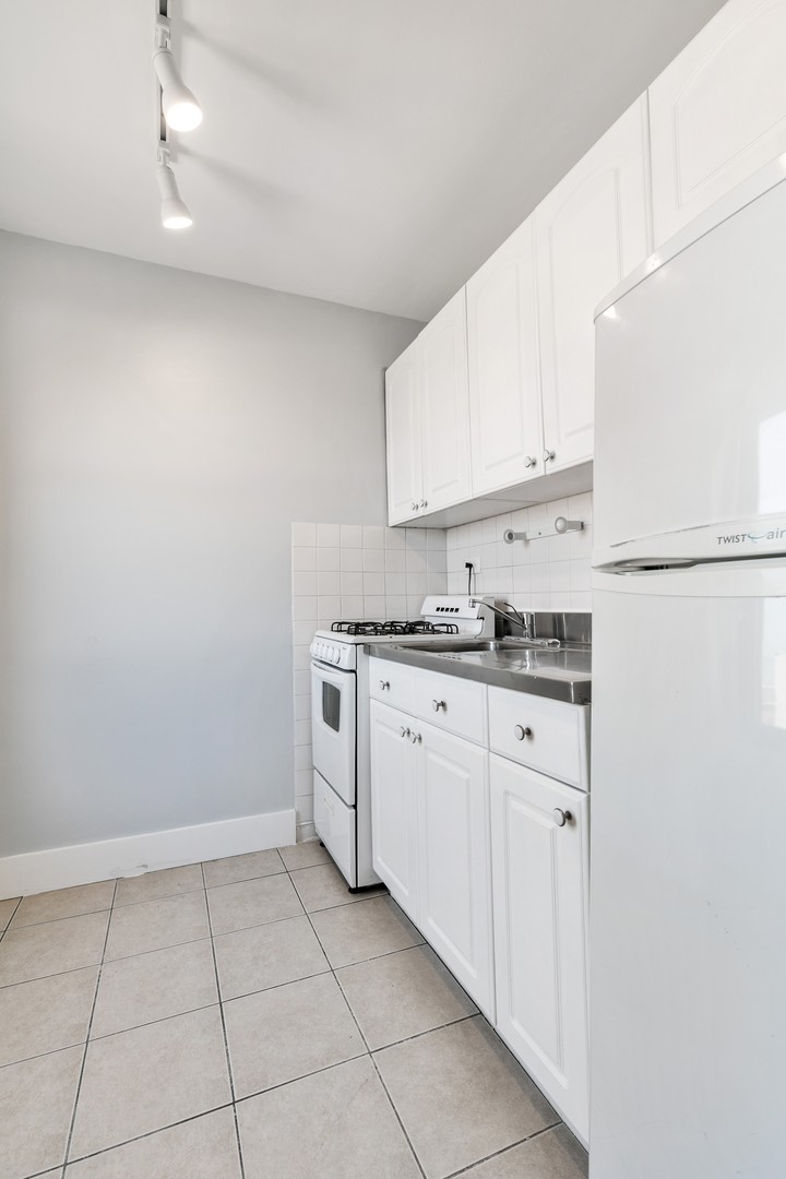 5858 North Sheridan Road, Unit 805 Chicago, IL 60660 - Photo 4 of 14 a kitchen with white cabinets and white appliances