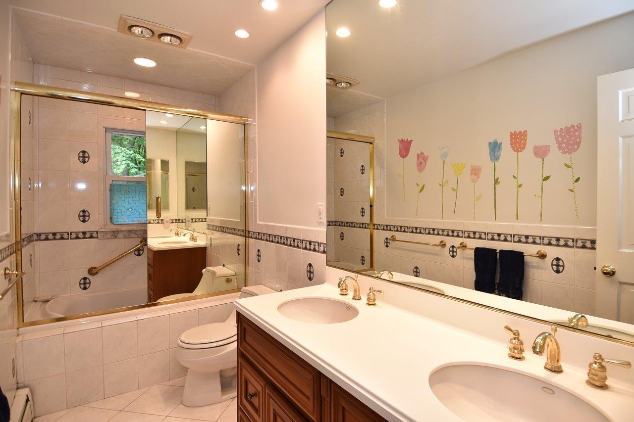 287 Briscoe Road New Canaan, CT 06840 - Photo 20 of 22 a bathroom with a granite countertop double vanity sink a mirror and a shower