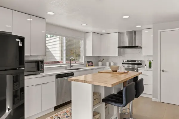 a kitchen with stainless steel appliances granite countertop a stove a sink a microwave a refrigerator and white cabinets
