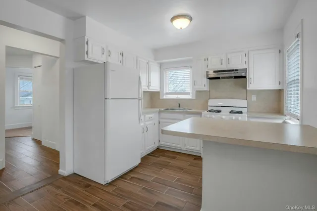 a kitchen with white cabinets and wooden floor