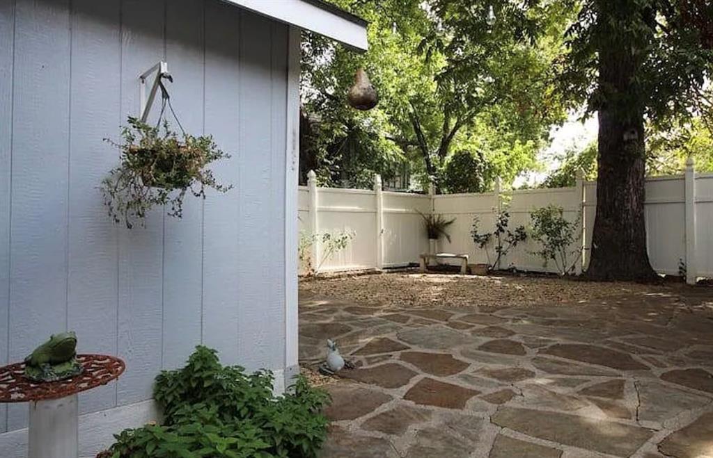 1718 Ripley Street Dallas, TX 75204 - Photo 27 of 33 Flagstone patio with a white privacy fence and mature trees