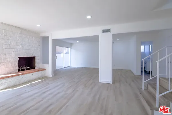 an empty room with wooden floor and fireplace