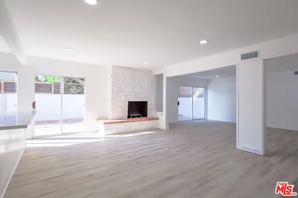 a view of an empty room with wooden floor and a fireplace