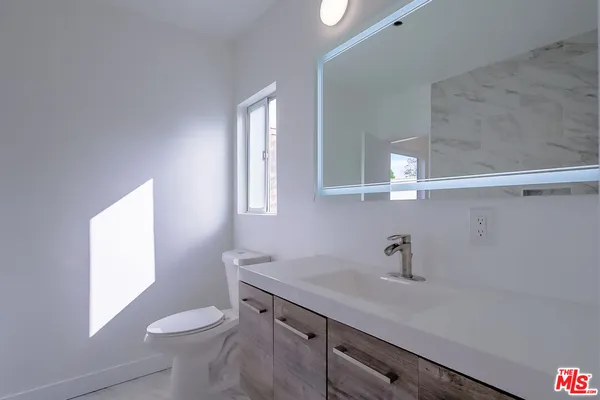 a bathroom with a sink a toilet a window and mirror