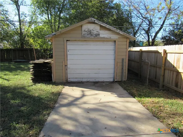 a view of backyard of house with wooden fence