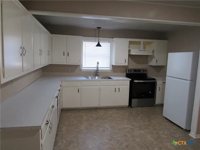 a kitchen with a sink a stove a refrigerator and cabinets