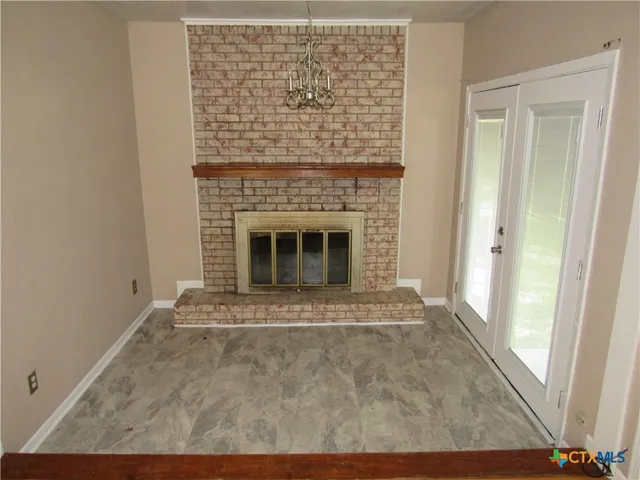 a view of an empty room with wooden floor fireplace and a window