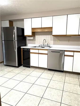 a kitchen with granite countertop a refrigerator and a stove top
