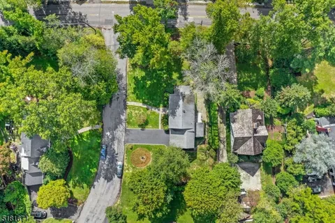 an aerial view of a house with outdoor space and trees all around