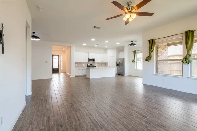 a view of a big room with wooden floor and a kitchen