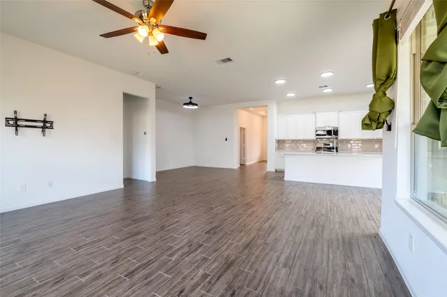 a view of a kitchen with wooden floor and a ceiling fan