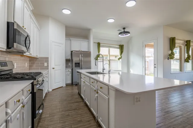 a large kitchen with stainless steel appliances granite countertop a lot of counter space and wooden floor