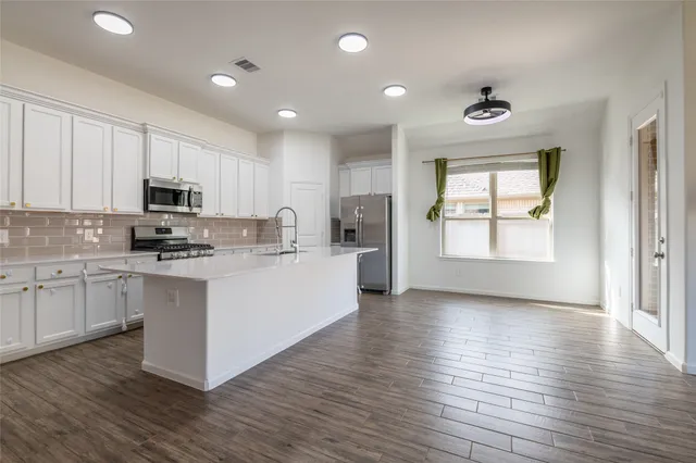 a kitchen with granite countertop a stove top oven a sink and white cabinets with wooden floor