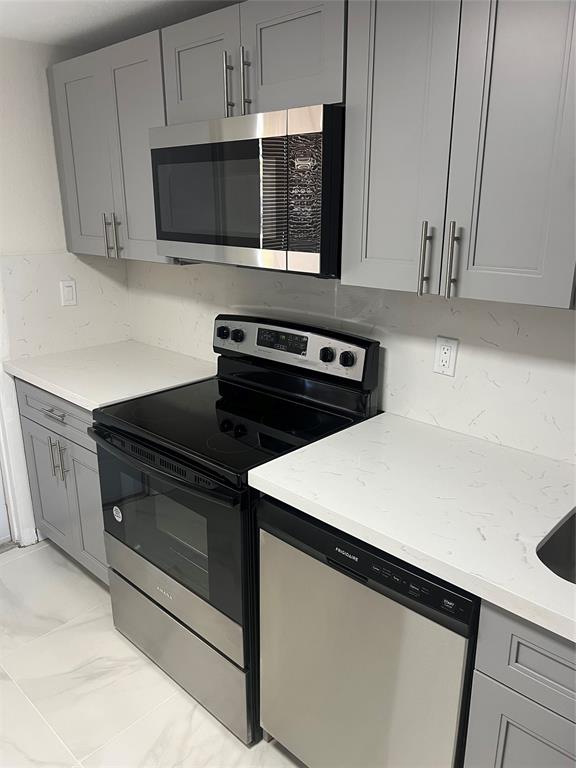 8705 Northwest 38th Drive, Unit 2A Coral Springs, FL 33065 - Photo 13 of 51 a kitchen with stainless steel appliances a stove microwave and sink
