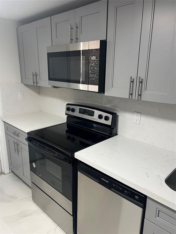 8705 Northwest 38th Drive, Unit 2A Coral Springs, FL 33065 - Photo 6 of 51 a kitchen with stainless steel appliances a stove a microwave a sink and cabinets