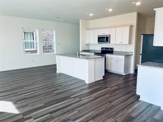 a kitchen with cabinets wooden floor and a fireplace