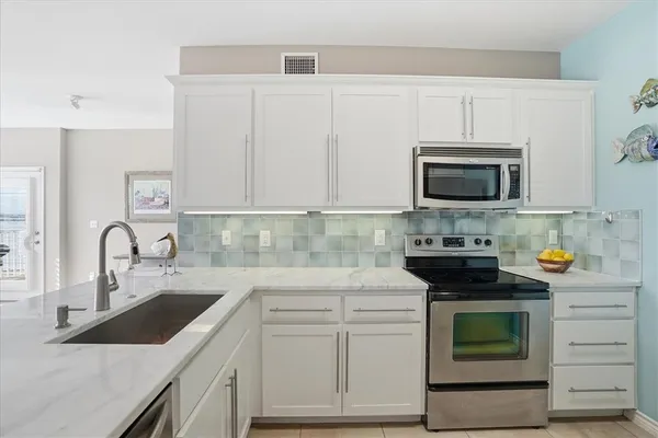 a kitchen with stainless steel appliances granite countertop white cabinets a stove top oven and dishwasher