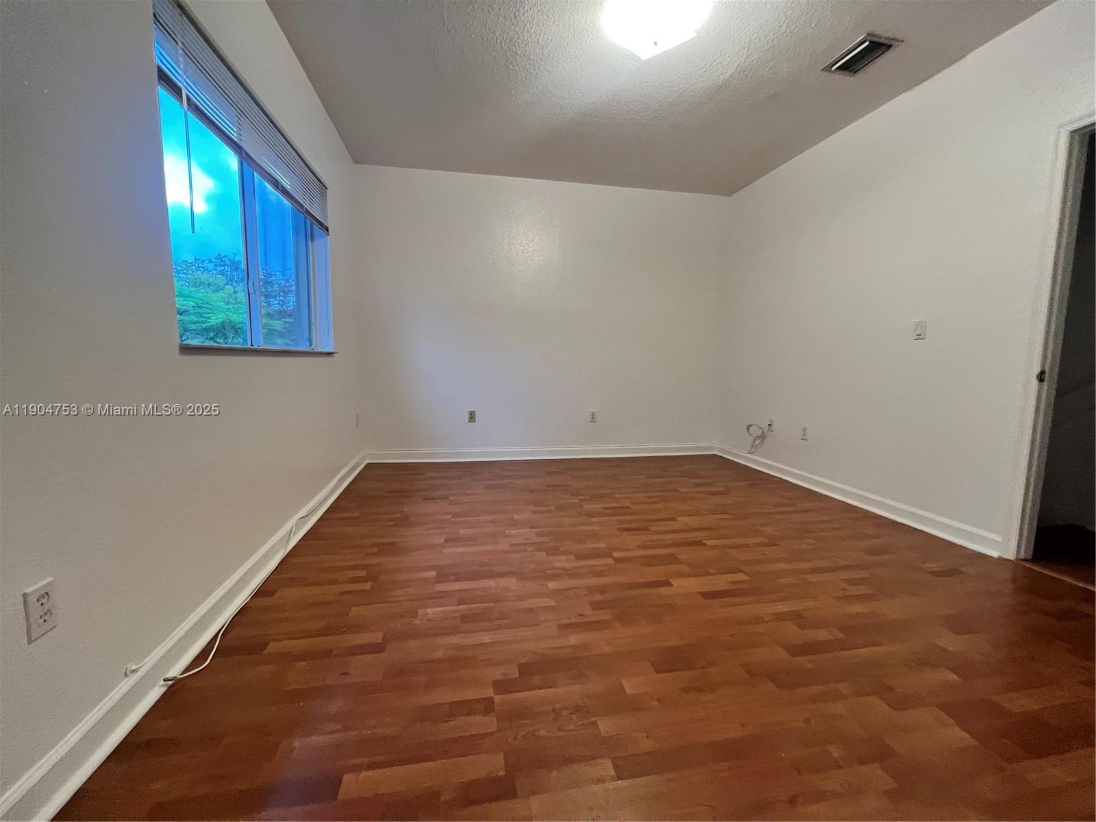 8564 Southwest 214th Way Cutler Bay, FL 33189 - Photo 14 of 31 an empty room with wooden floor and windows