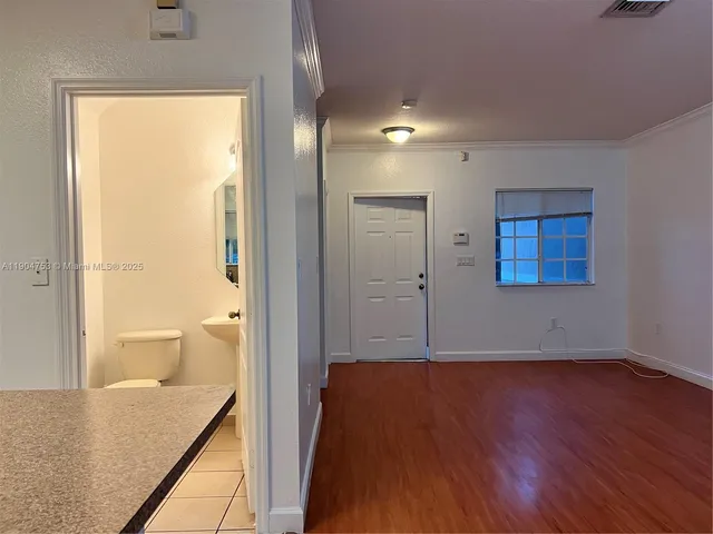 a view of a hallway with wooden floor and a bathroom