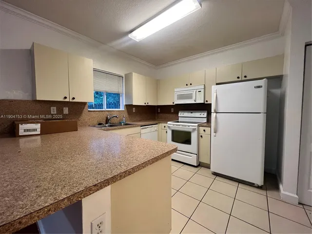 a kitchen with granite countertop a refrigerator a stove a sink a microwave and island