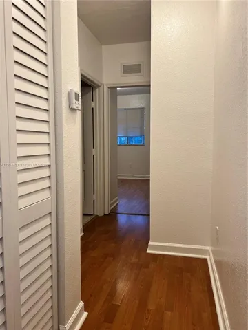 an empty room with wooden floor cabinet and windows