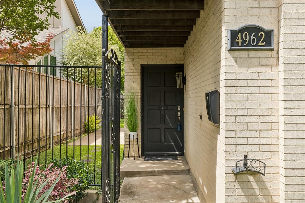 4962 Thunder Road Dallas, TX 75244 - Photo 4 of 26 Entryway featuring wrought iron fence and gate, solid door, light brick facade, and pretty landscaping.