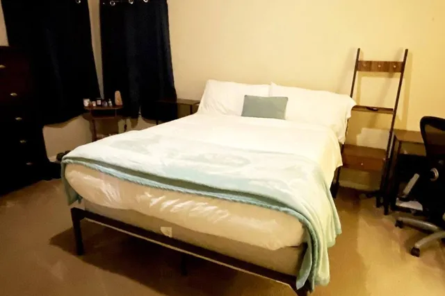 a bedroom with a bed and teddy bear on bed