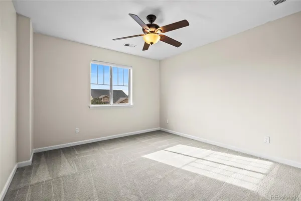 an empty room with ceiling fan and window