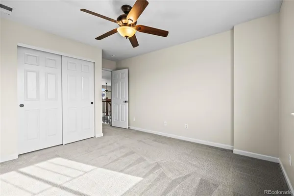 an empty room with closet and a ceiling fan