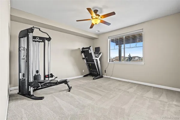 an empty room with chandelier fan and windows