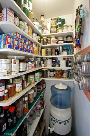 a room with stainless steel appliances a rug and a book shelf