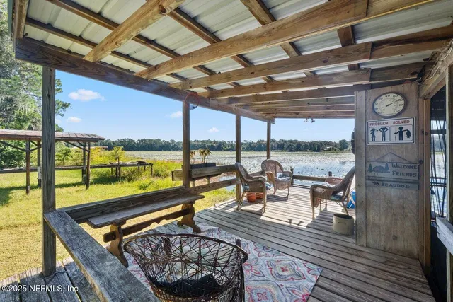 a living room with patio furniture and a floor to ceiling window next to a yard